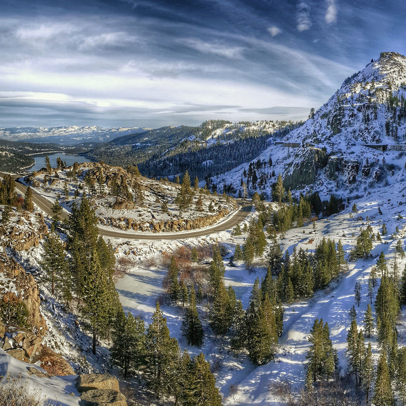 Snowy mountain landscape with a winding road and trees at Donner Pass, CA, In Winter