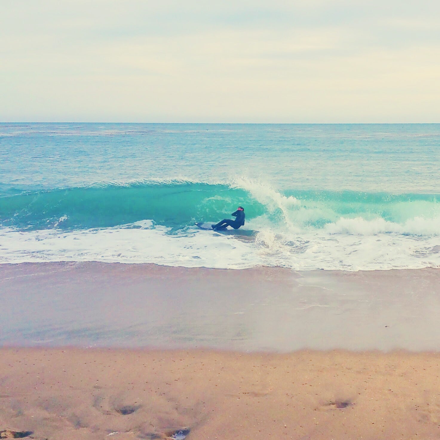 Person skimboarding on a wave at the beach in Santa Cruz, CA