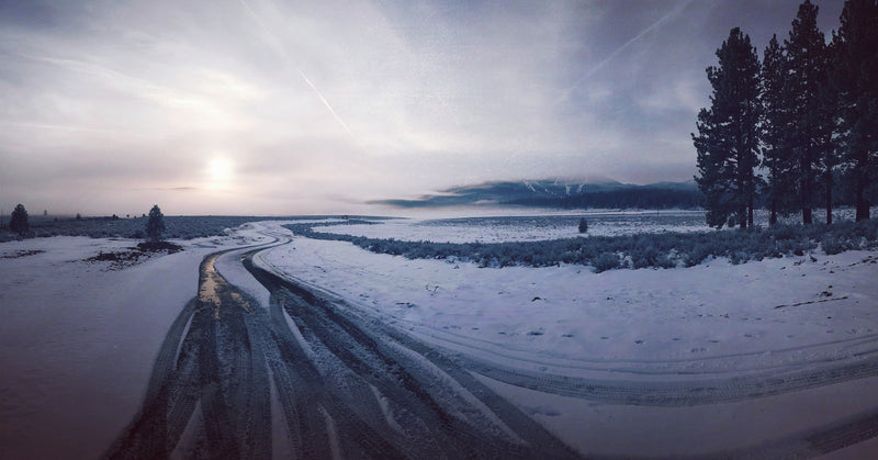Truckee, CA - Winding road through a snowy landscape with trees and mountains in the distance.