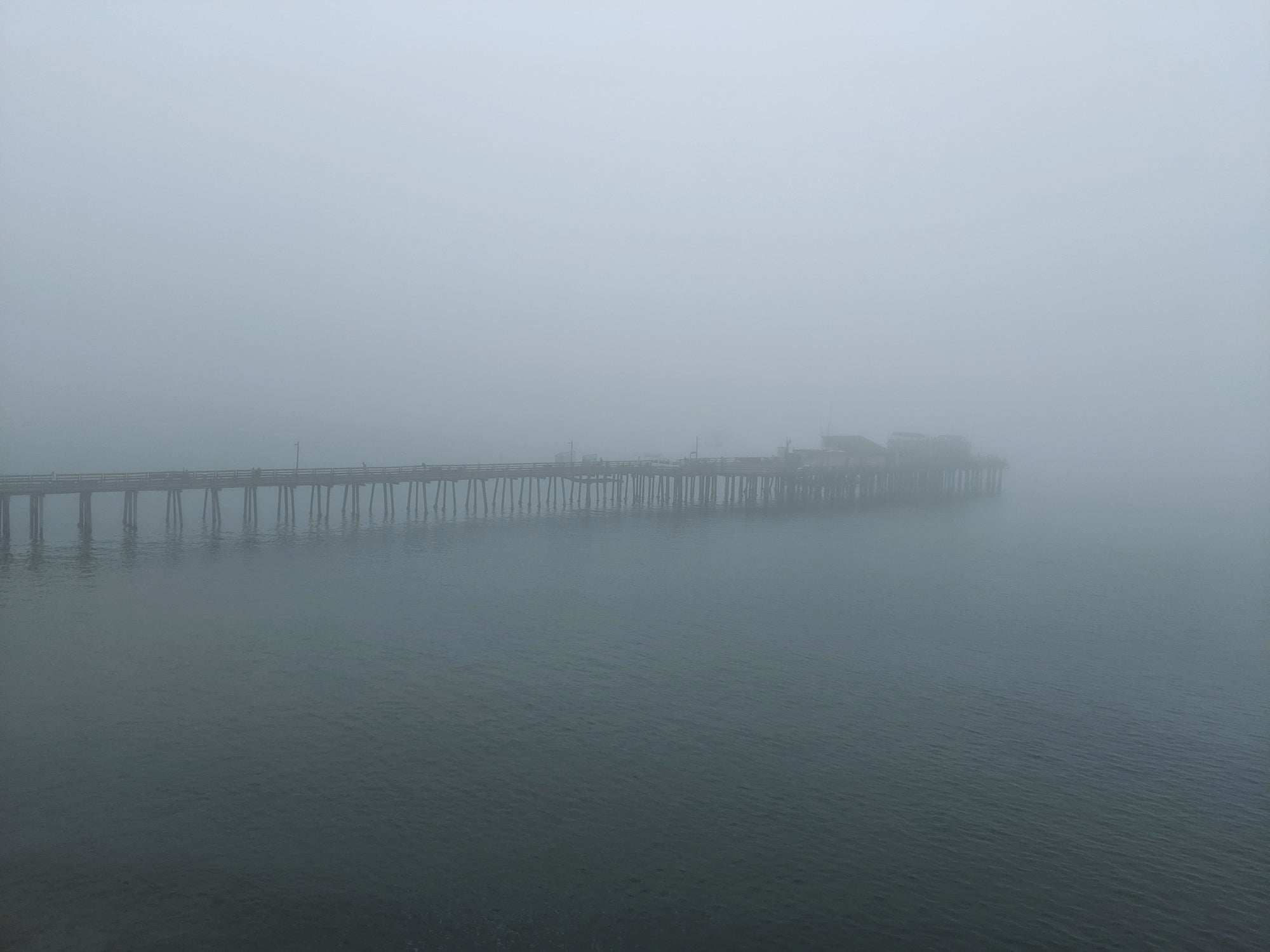 Long pier extending into a foggy body of water in Capitola Beach, CA